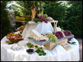 Rustic platters table with imported cheese wheels and antipasto platters at a Tuscan style backyard wedding