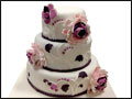 fondant covered white wedding cake with pink and purple flowers for a Long Island wedding