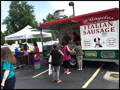 our carnival style italian sausage and pepper truck is surrounded by people at a catered event on Long Island
