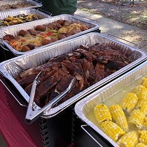 A tempting BBQ plate with juicy ribs, fresh corn, savory sausage, and bright peppers, perfect for summer gatherings.