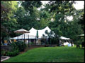 beautiful party tent and umbrella tables set in a backyard for party catering to offer shade in a hot summer day