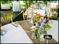 tables are set in mint and burlap with wild flowers in mason jars for a catered backyard wedding on Long Island