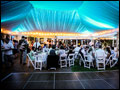 Long Island wedding party with Tuscan Style catering in full swing in a lit party tent featuring a black dance floor